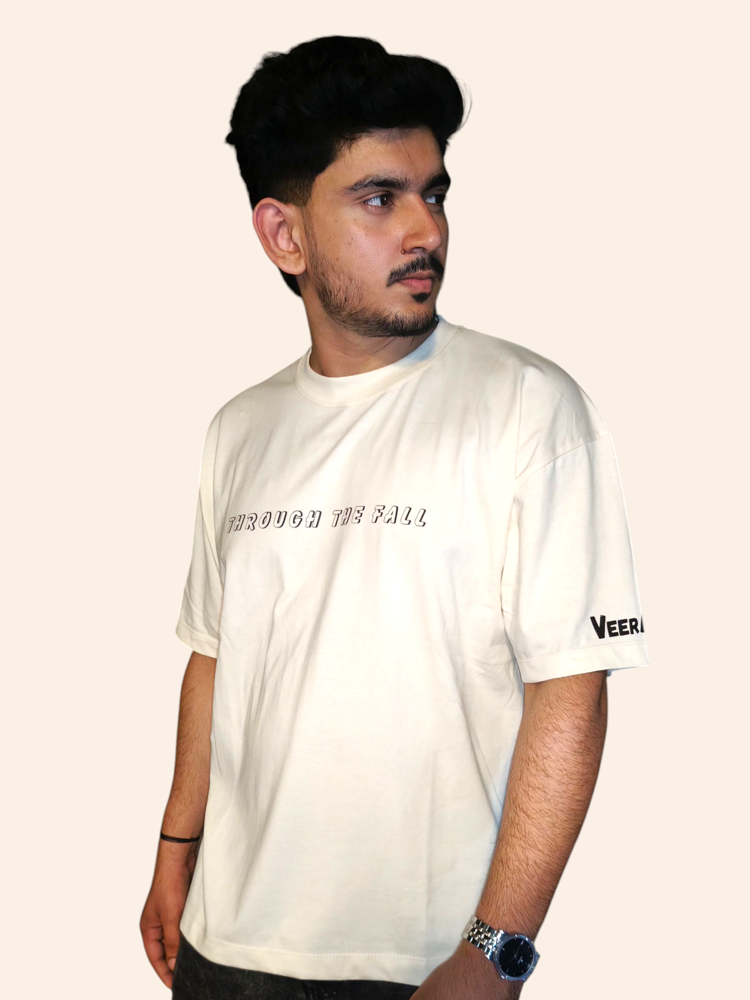 Man wearing a white VeerAstra t-shirt with text and branding on a plain background
