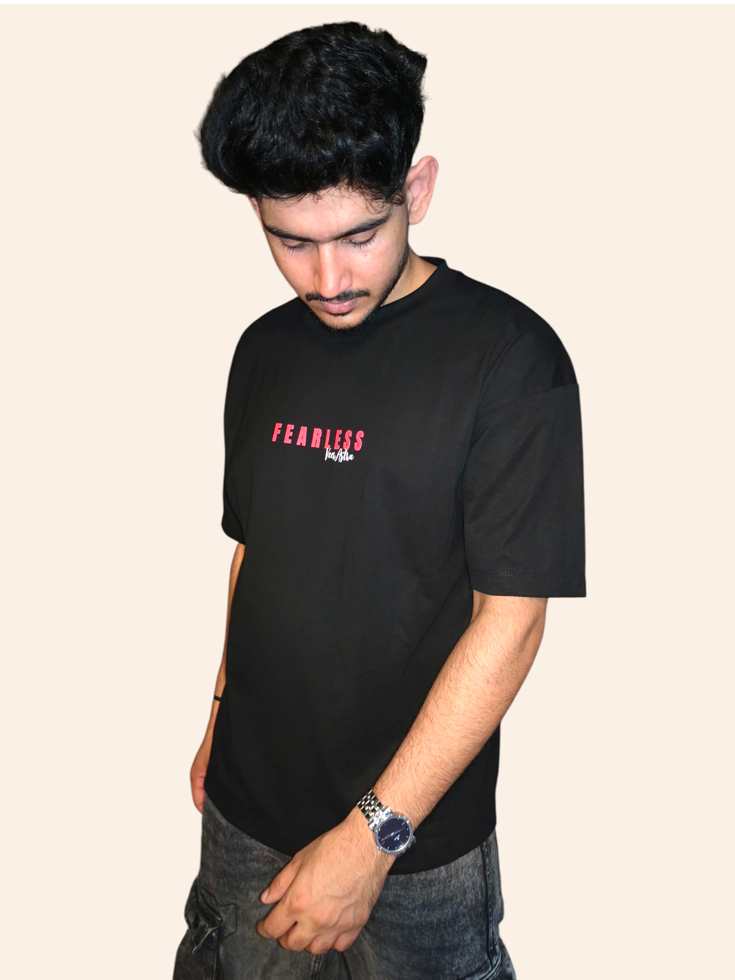 Person wearing a black VeerAstra t-shirt with red text on a beige background
