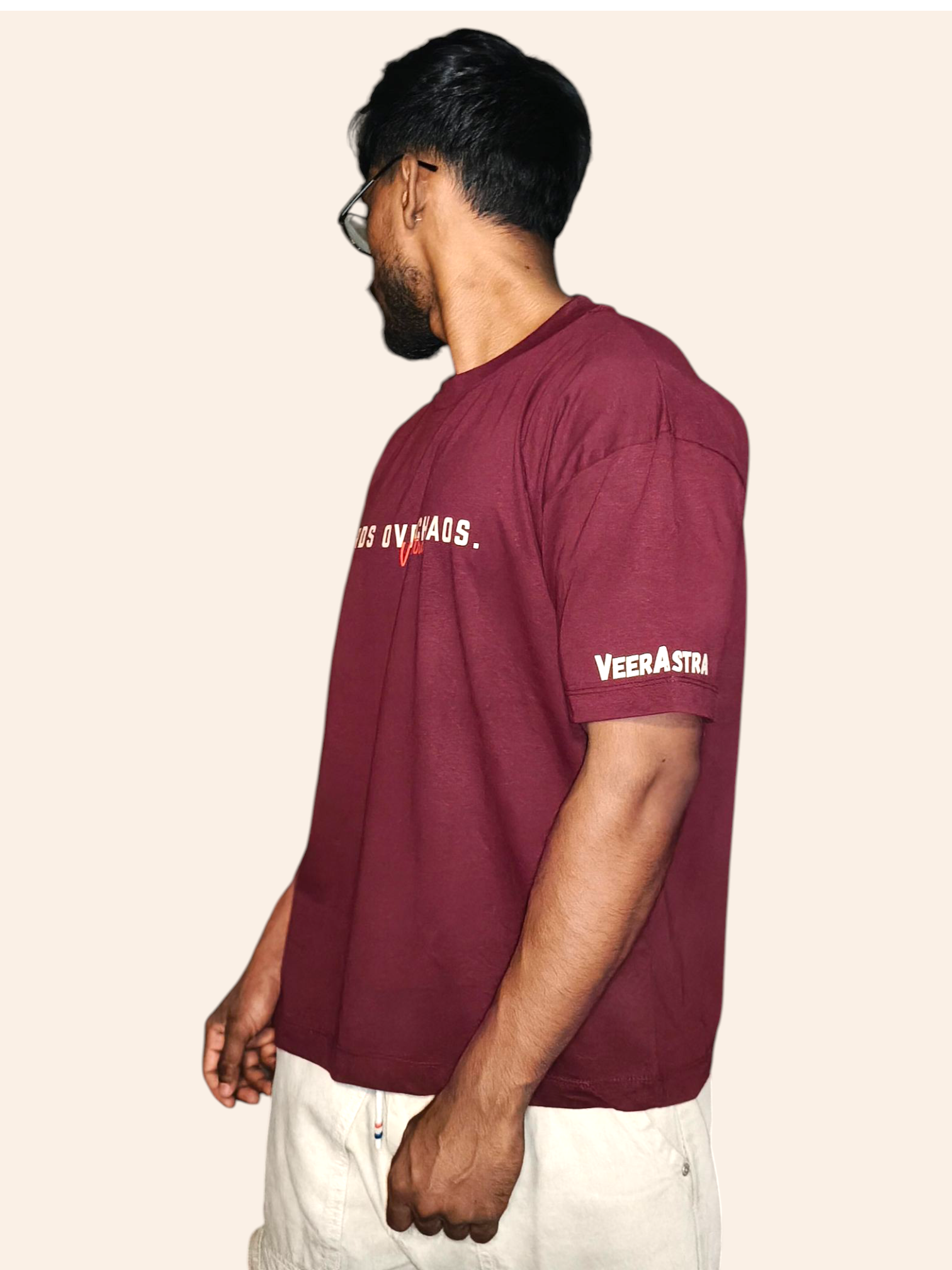 Man wearing a VeerAstra maroon t-shirt with branding on a beige background