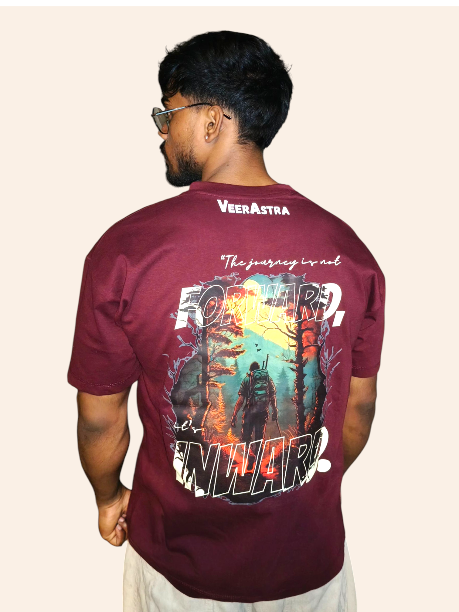 Man wearing a VeerAstra maroon t-shirt with a colorful graphic and text on the back, standing against a plain background.