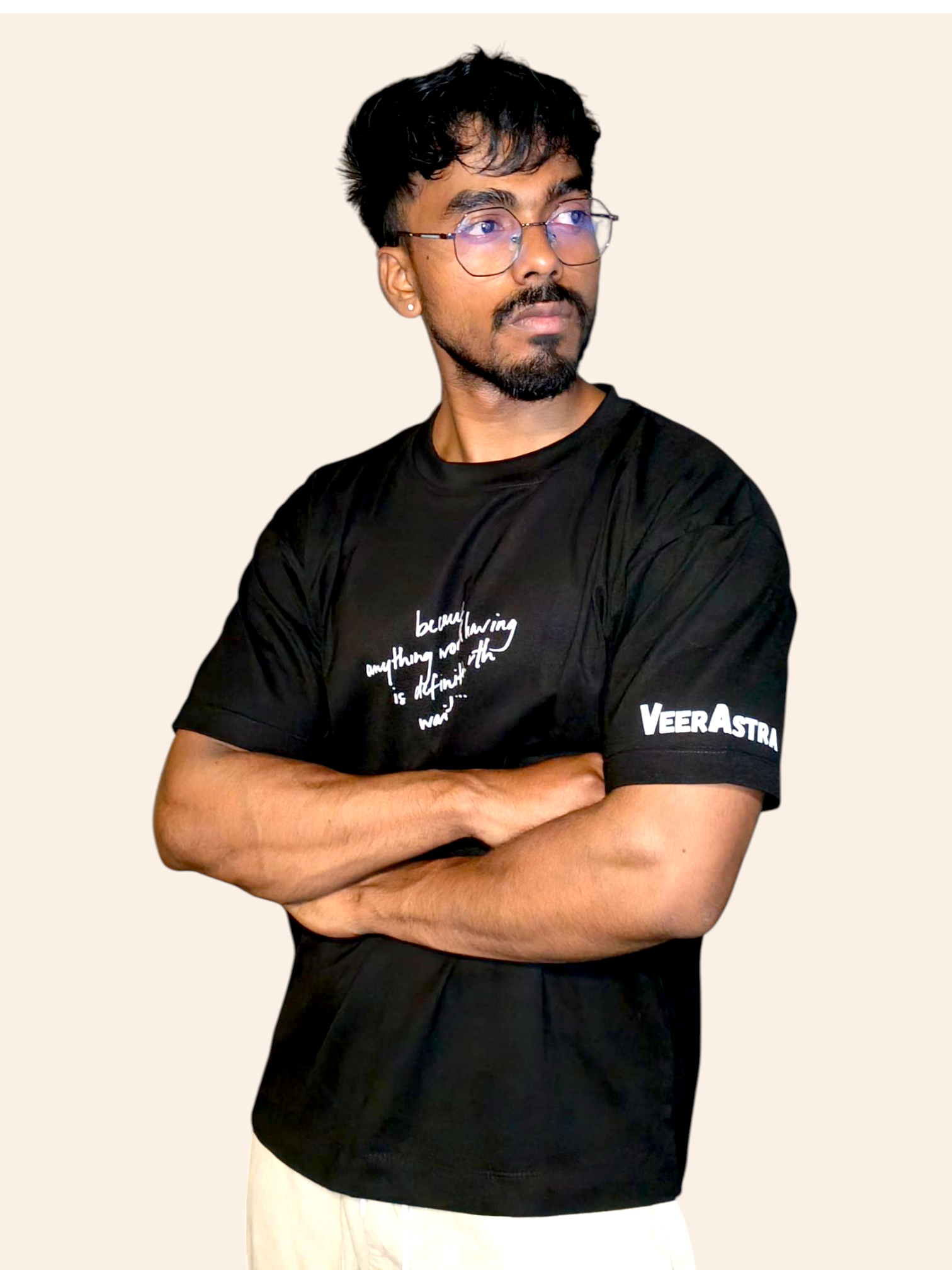 Man wearing a black classic VeerAstra t-shirt with text and branding on a beige background