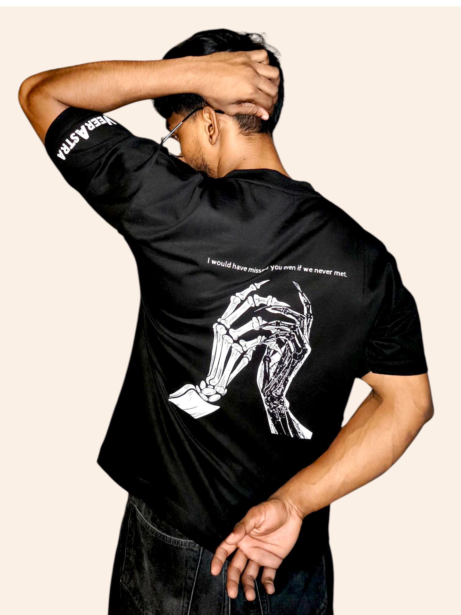 Person wearing a black classic VeerAstra t-shirt with a white graphic and text on a beige background