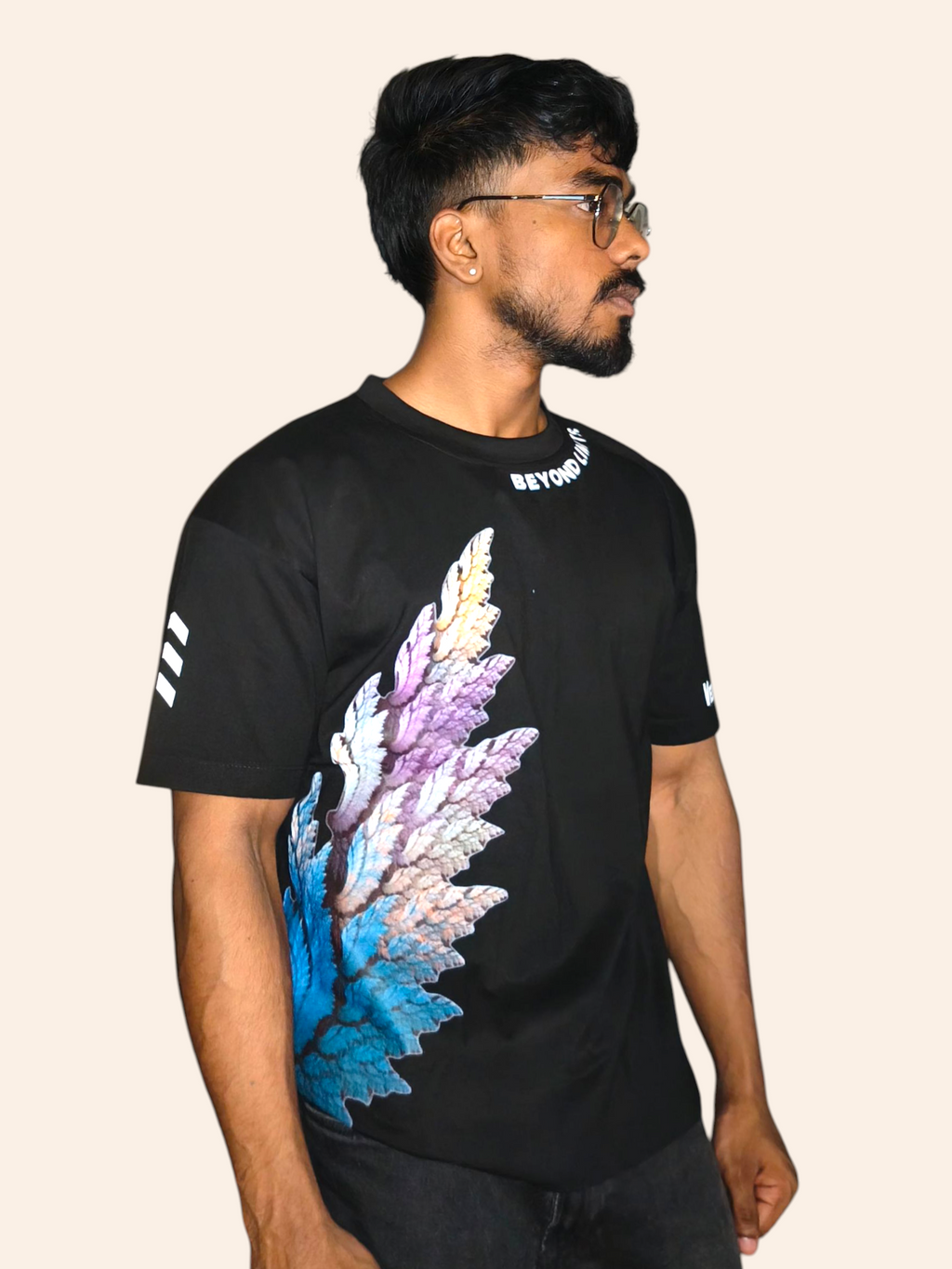 Man wearing a black VeerAstra t-shirt with colorful wing design on a beige background