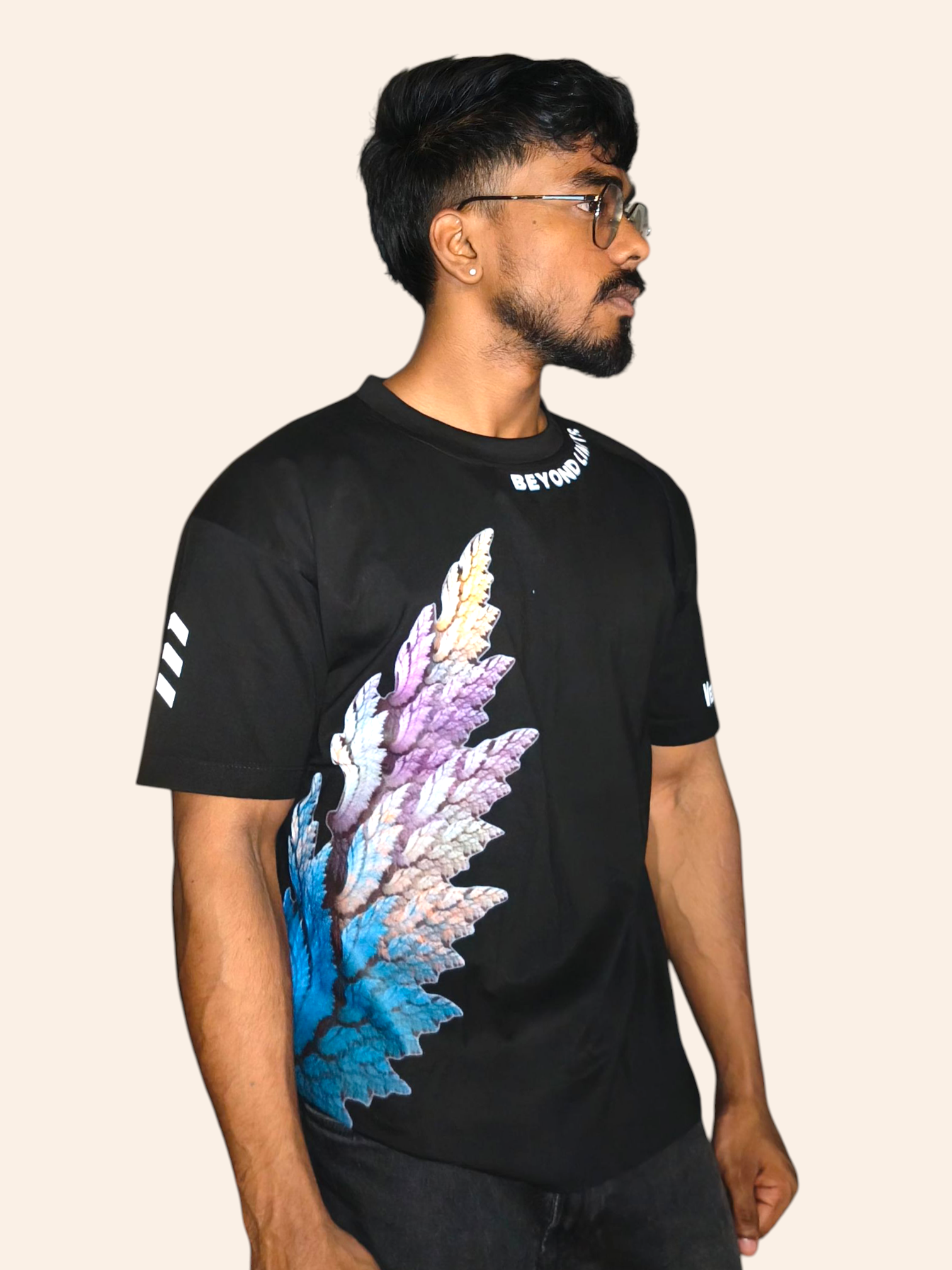 Man wearing a black VeerAstra t-shirt with colorful wing design on a beige background