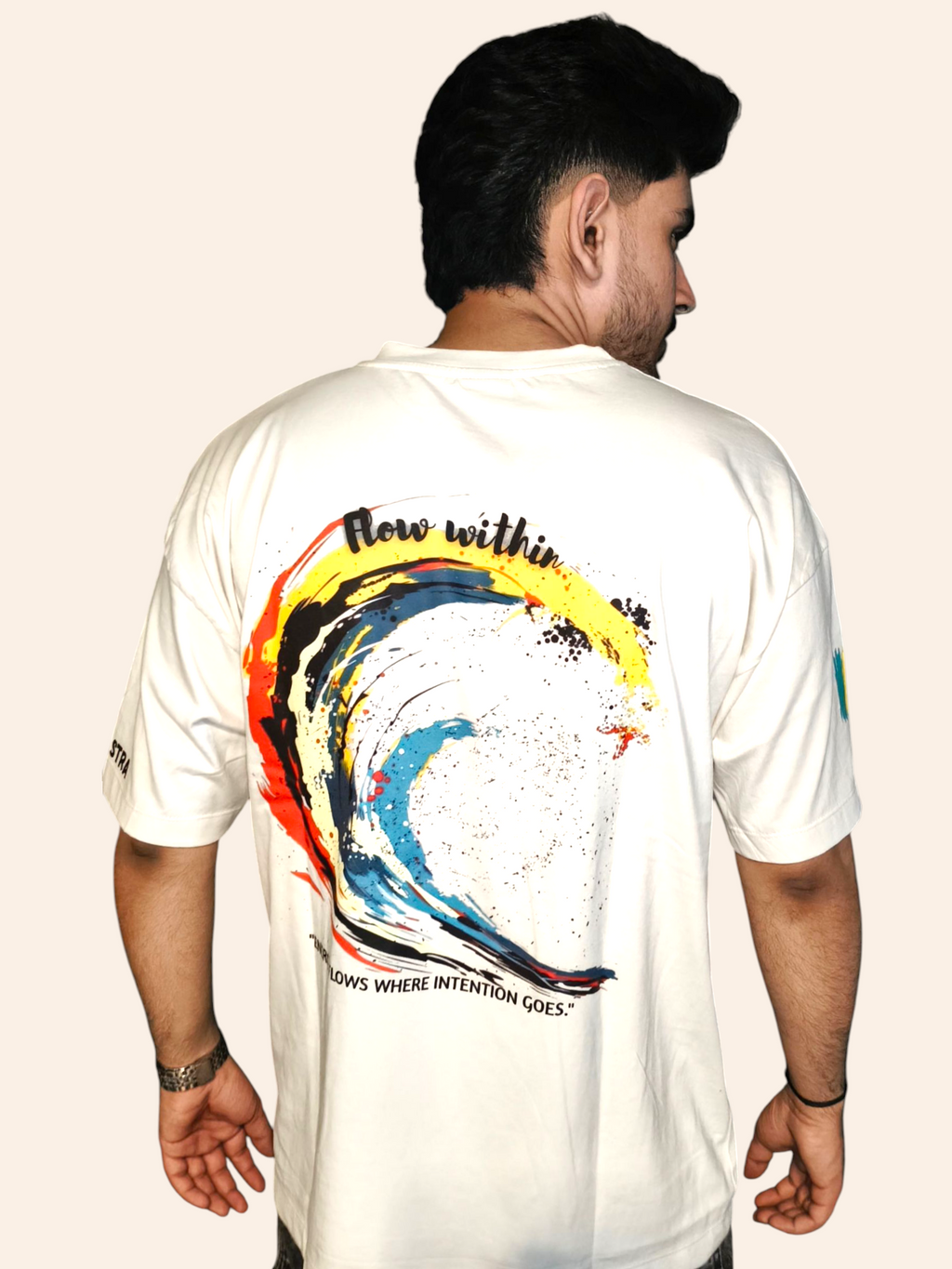 Person wearing a VeerAstra white t-shirt with a colorful design on the back against a plain background