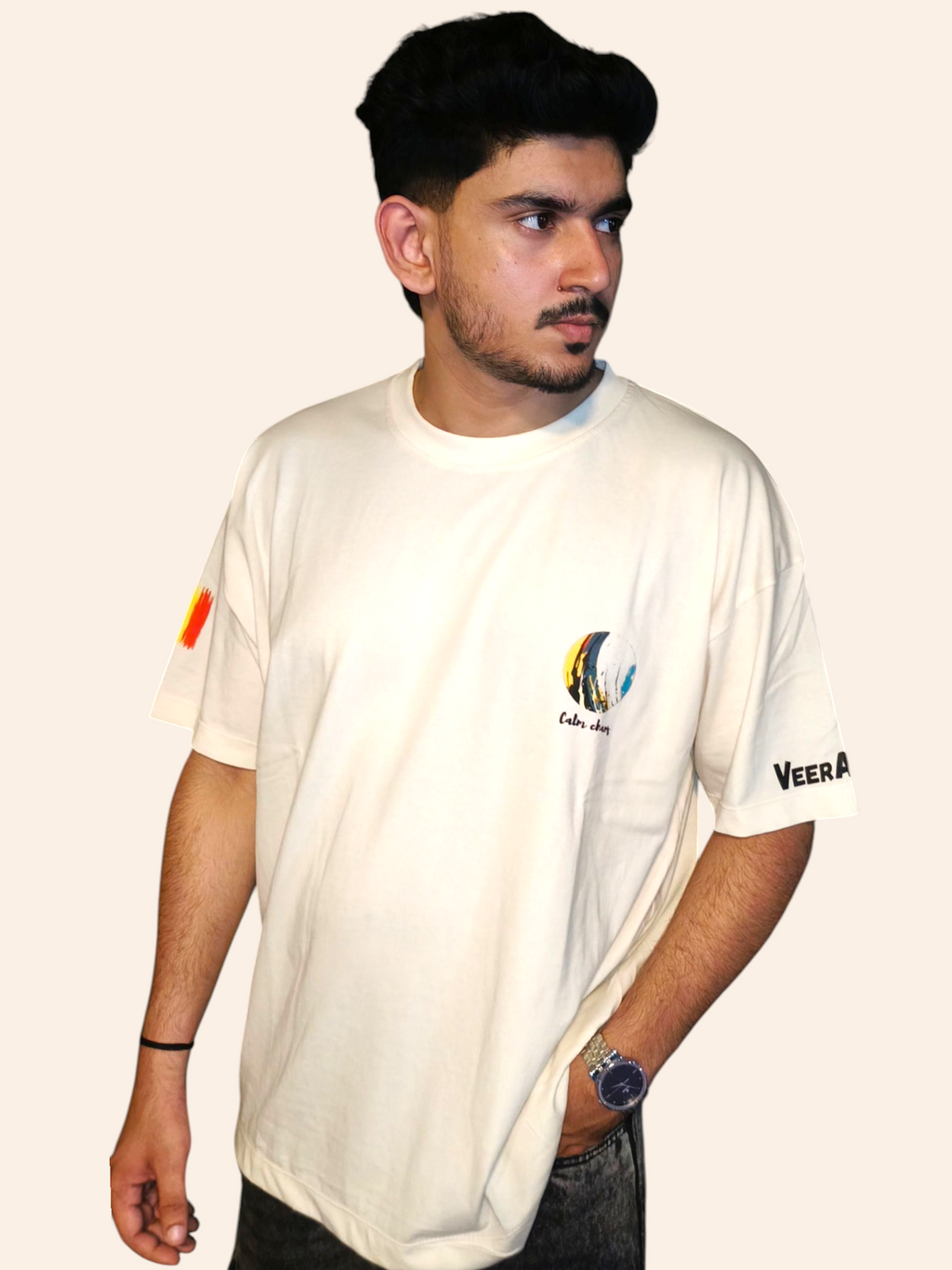 Person wearing a VeerAstra white t-shirt with logos on the sleeves against a plain background
