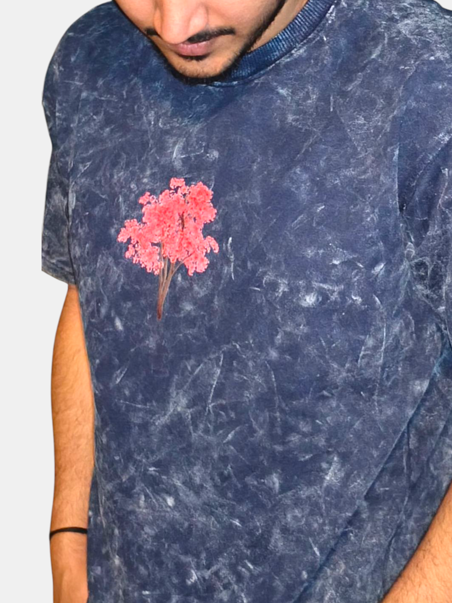 Person wearing a VeerAstra blue acid wash t-shirt with a pink floral design on a plain background