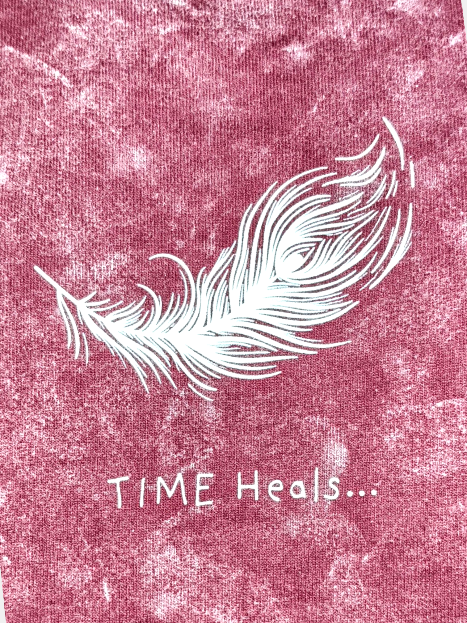 White feather graphic with 'TIME Heals...' text on a textured VeerAstra Burgundy acid wash t-shirt