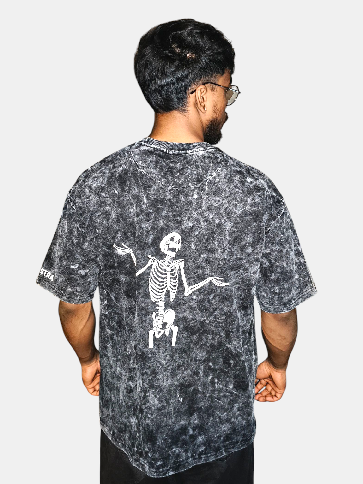 Person wearing a VeerAstra black acid-wash t-shirt with a skeleton design on the back, standing against a white background.