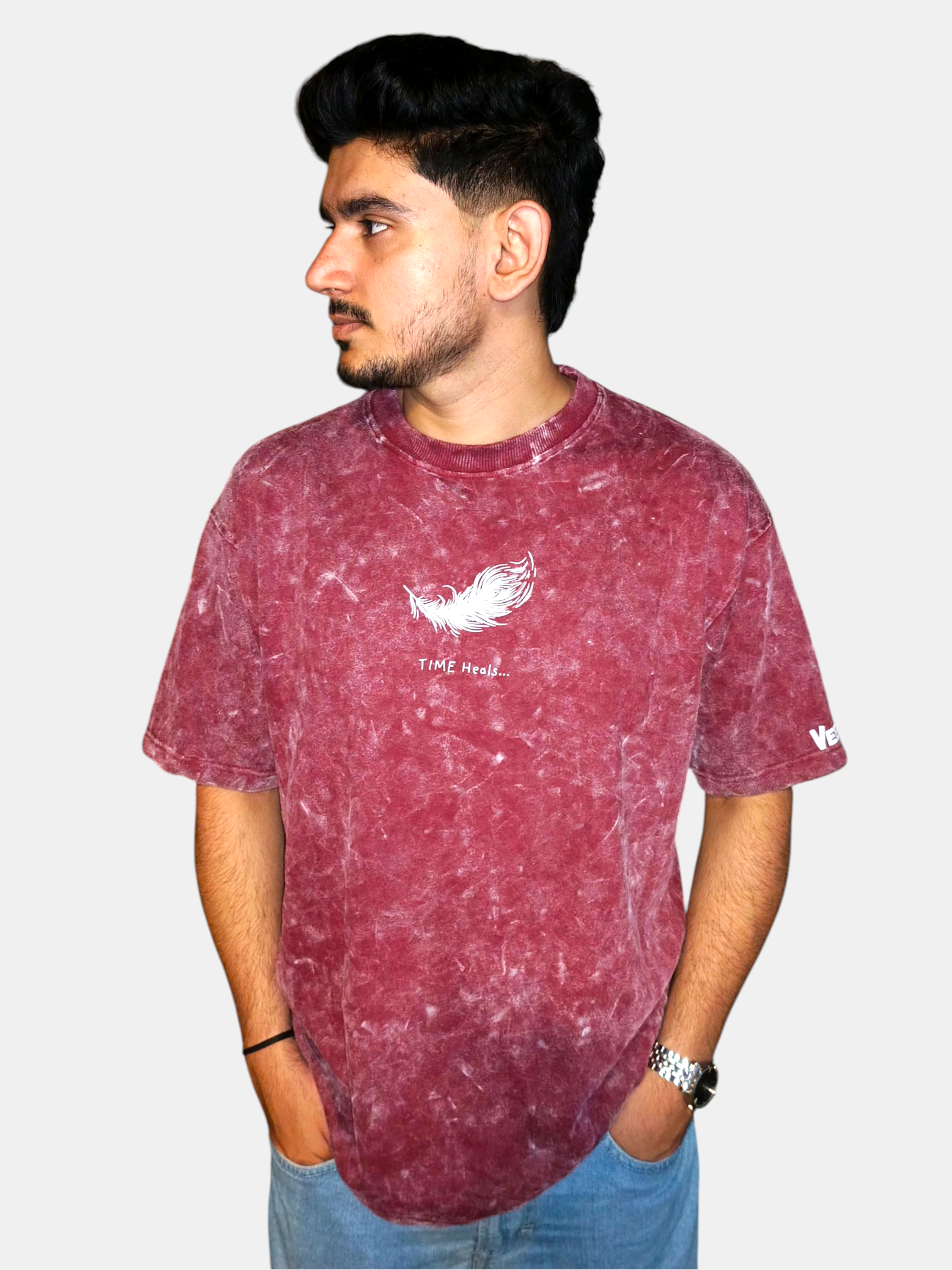 Man wearing a VeerAstra Burgundy acid wash t-shirt with a logo on a plain background